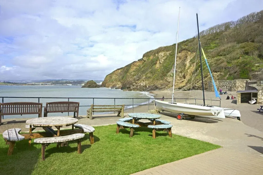 Polkerris Beach and harbour, a small sandy beach sheltered by a historic harbour wall on the shores of St Austell Bay.